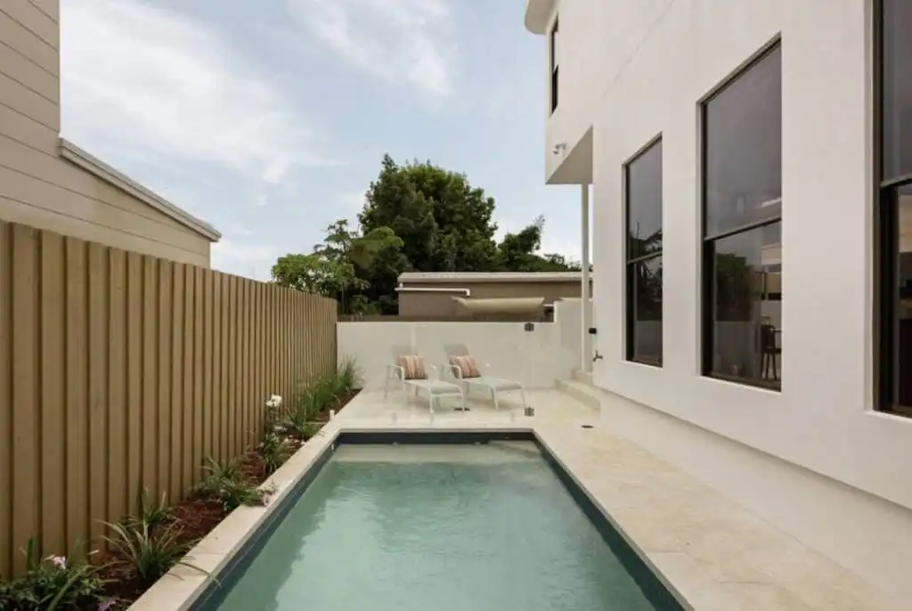 Classic Light Travertine tiles installed around a narrow swimming pool at a contemporary Queensland home