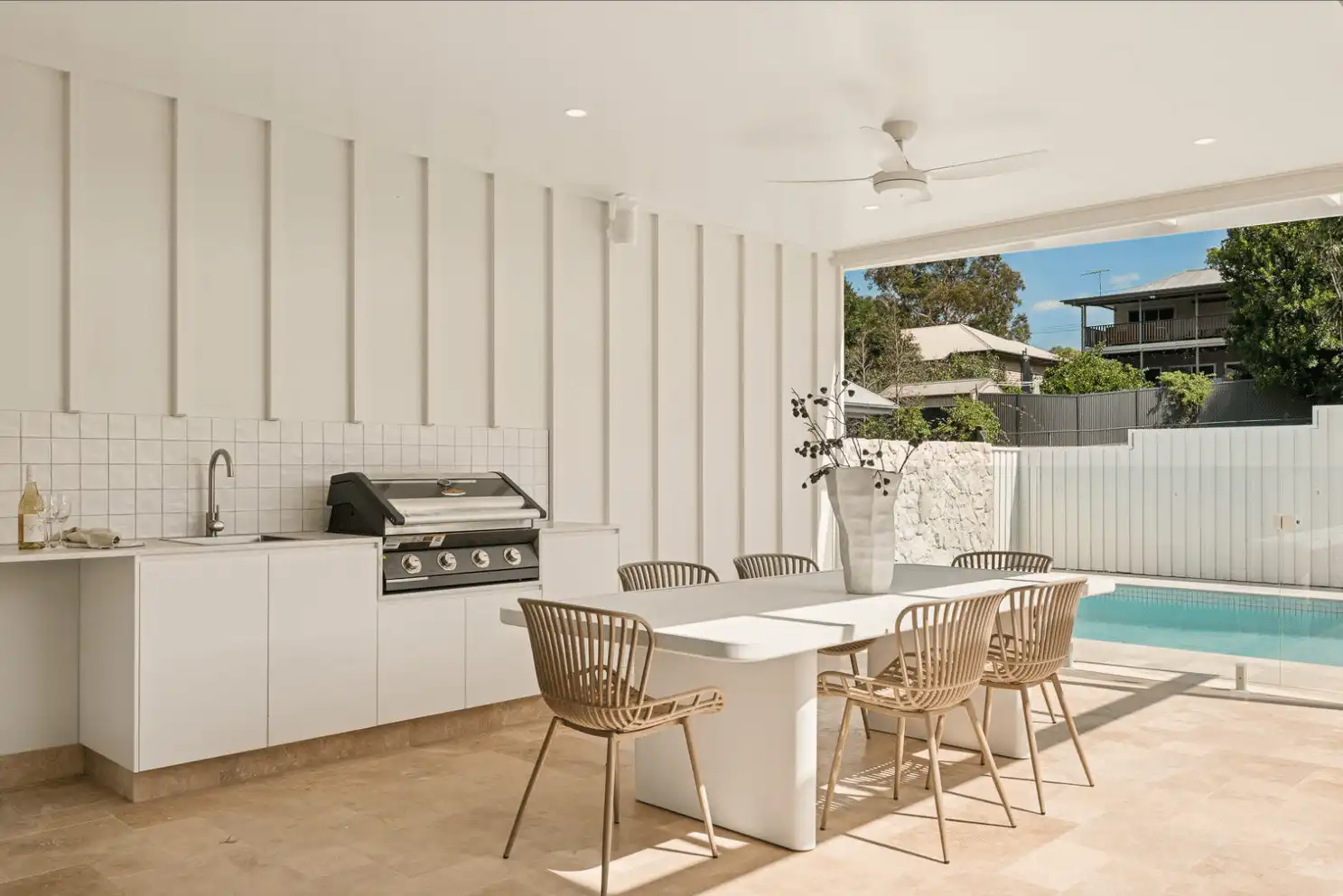 View from an outdoor patio overlooking a swimming pool featuring Terra Travertine loose random wall cladding as a natural stone feature wall.