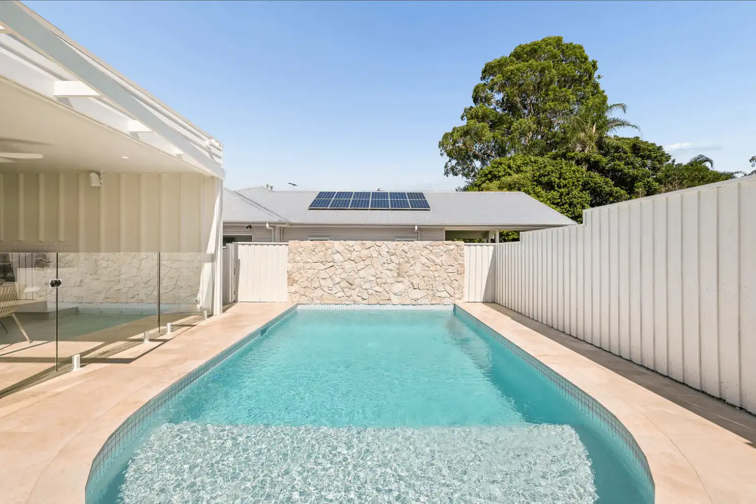 Terra Travertine loose random wall cladding installed as a natural stone feature wall surrounding a luxury swimming pool.