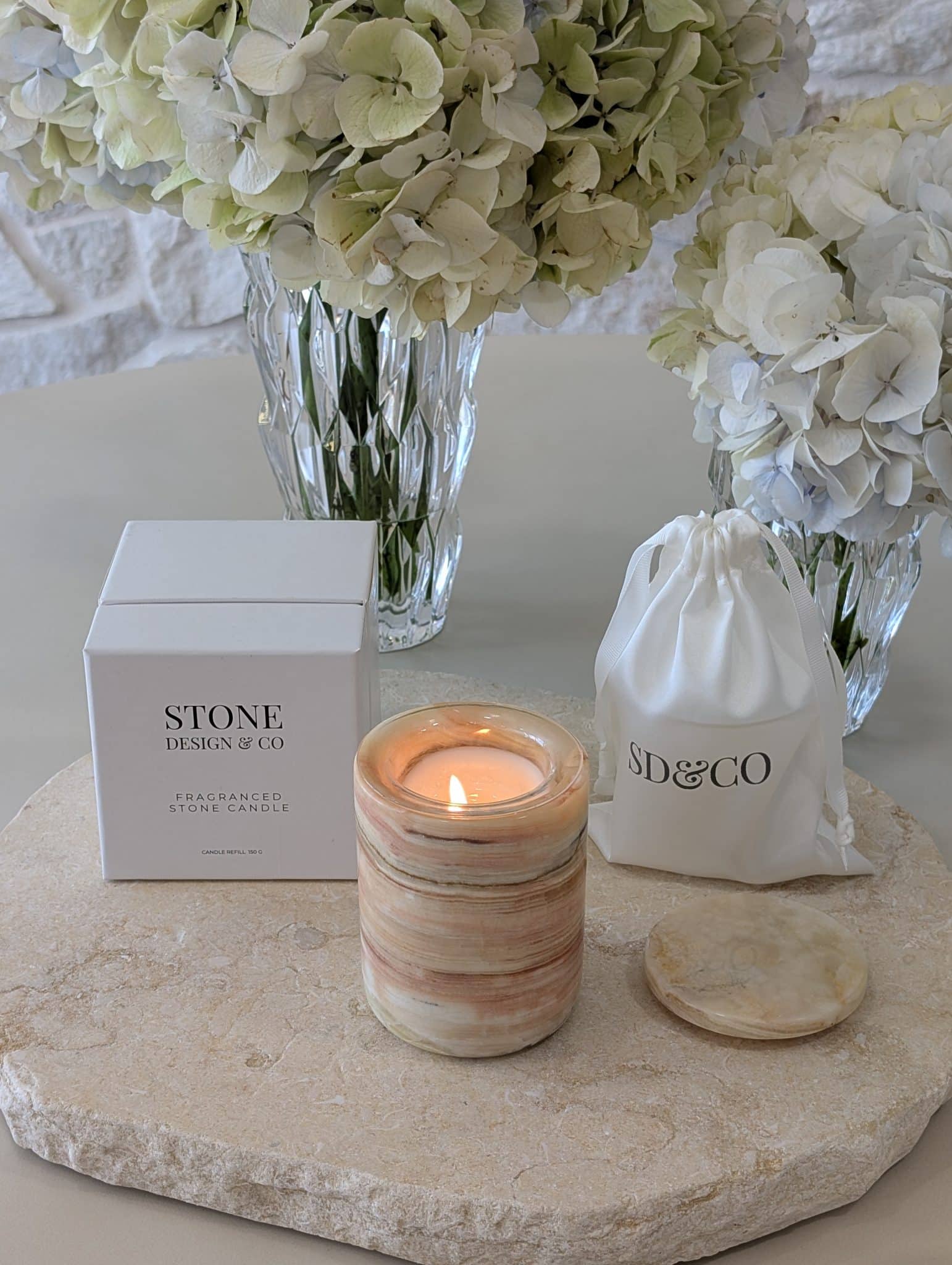 Natural onyx stone candle lit with refillable insert, styled with Stone Design & Co packaging